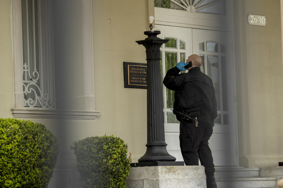 A Secret Service officer looks at a bullet hole after police say a person with an assault rifle opened fire at the Cuban Embassy, Thursday, April 30, 2020, in Washington. Officers found the suspect with an assault rifle and took the person into custody without incident, police said. (AP Photo/Andrew Harnik)