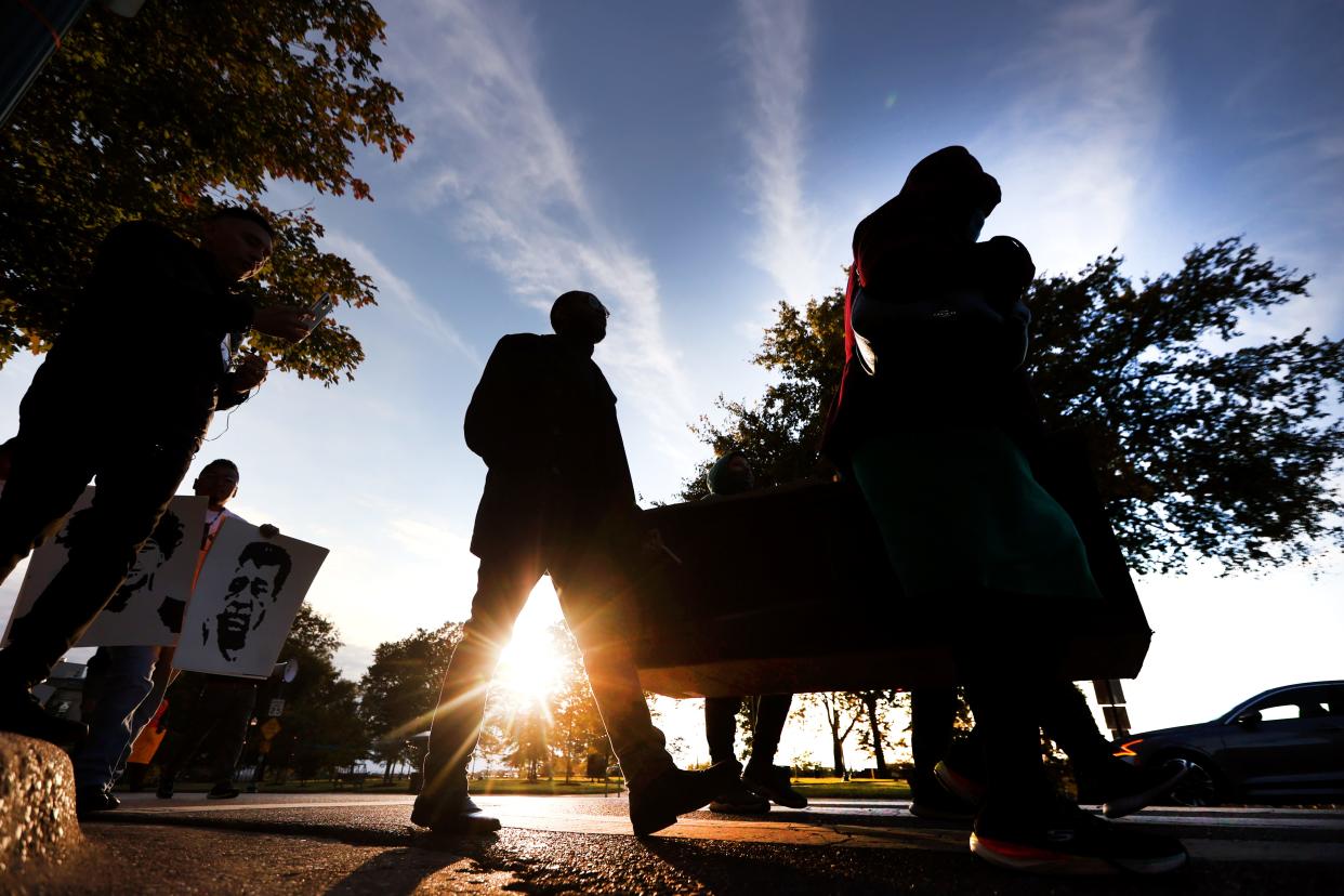 People parade downtown, carrying a cardboard coffin to represent homicide victims and demand that city authorities work to reduce gun violence in Memphis, Tenn. on Tuesday, Nov. 2, 2021. 