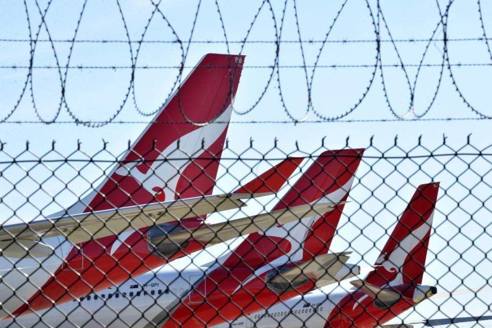 A photo of Qantas planes through a barbed wire fence.