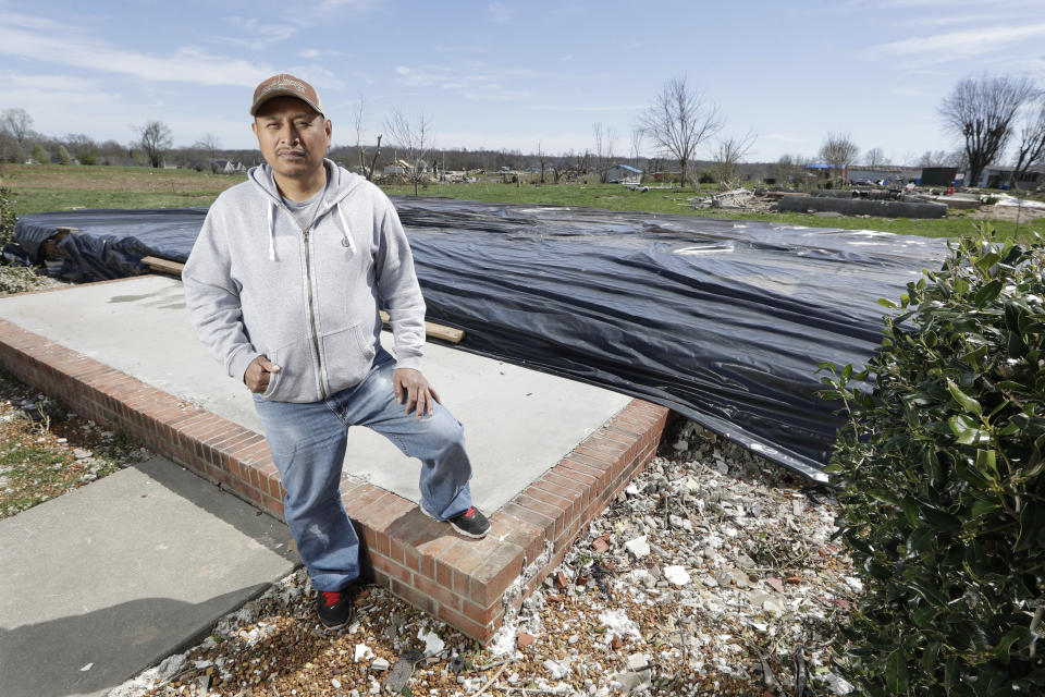 In this March 26, 2020, photo, Jose Cojom stands on the front step of what remains of his home after it was destroyed by a tornado in Cookeville, Tenn. Like thousands of other Middle Tennesseans, Cojom's life has been upended by back-to-back disasters. Residents still reeling from the deadly twisters of March 3 now have to confront life in the age of coronavirus. (AP Photo/Mark Humphrey)