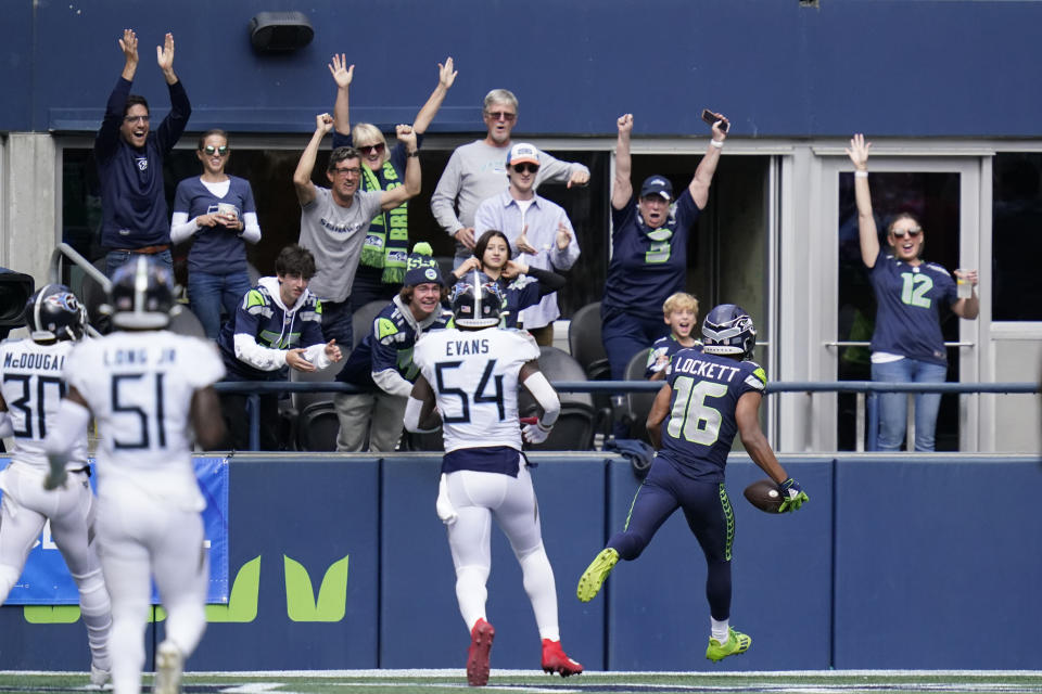 Fans cheer as Seattle Seahawks wide receiver Tyler Lockett (16) scores a touchdown in front of Tennessee Titans inside linebacker Rashaan Evans (54) during the first half of an NFL football game, Sunday, Sept. 19, 2021, in Seattle. (AP Photo/Elaine Thompson)