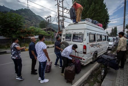 Indian tourists load their luggage onto a passenger vehicle as they prepare to leave Srinagar