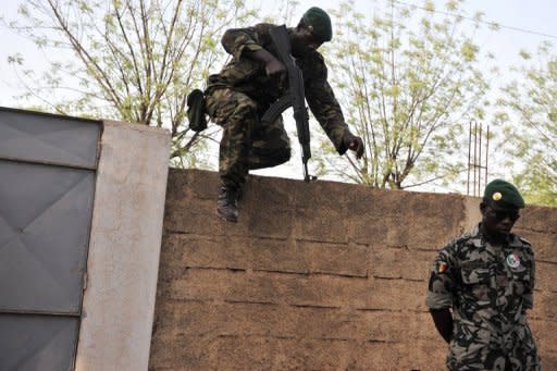 A Malian soldier leaps over a wall as another stands guard on April 3, 2012 at the Kati military camp near Bamako. The soldiers who staged a putsch in Mali five weeks ago say they have defeated an overnight counter-coup by foreign-backed forces loyal to ousted president Amadou Toumani Toure