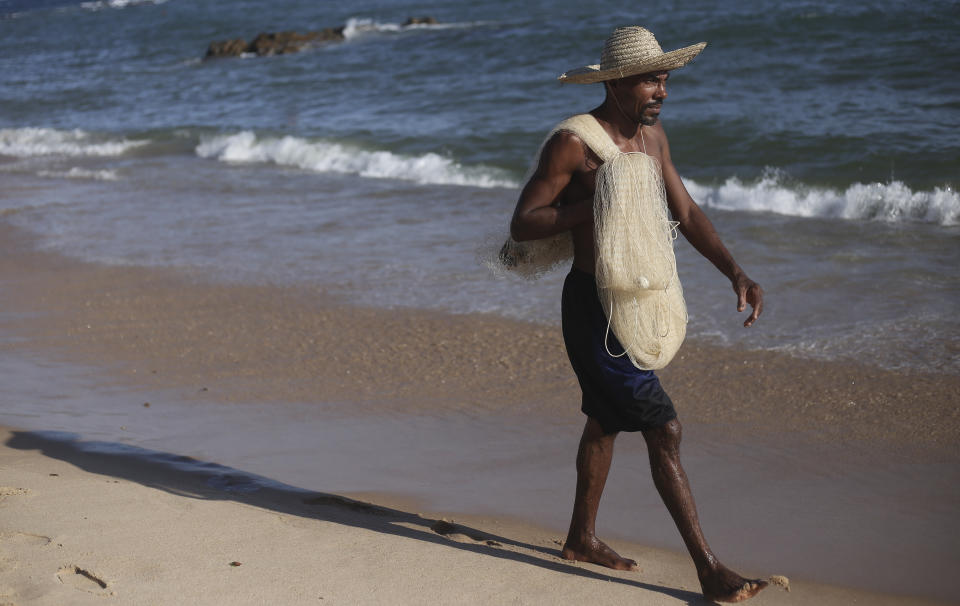 Arivaldo Sousa walks carrying a fishing net at Itapua beach in Salvador, Brazil, Saturday, Oct. 26, 2019. Sousa normally harvests 175 pounds (80 kilograms) of lobster per month but has fished a mere fraction of that recently, with hotels and restaurants no longer buying for fear of contamination from an oil spill in the region. (AP Photo/Raphael Muller)