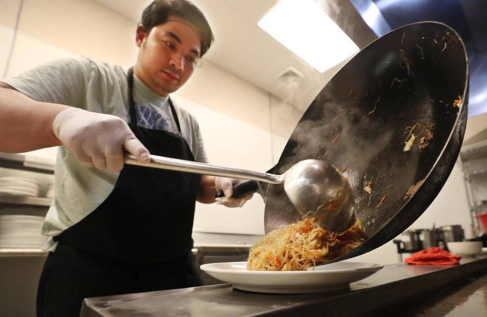 Sike Lawi, co-owner  of Live Mon Thai-Malay restaurant, plates Singapore noodles with tofu in the kitchen of the Akron restaurant on Brittain Road.