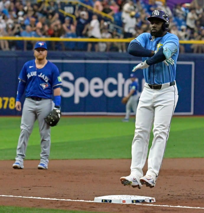 Toronto Blue Jays’ Justin Turner, left, watches as Tampa Bay Rays’ Randy Arozarena leaps on third base as he celebrates a solo home run during the first inning of a baseball game, Sunday, March 31, 2024, in St. Petersburg, Fla. (AP Photo/Steve Nesius)