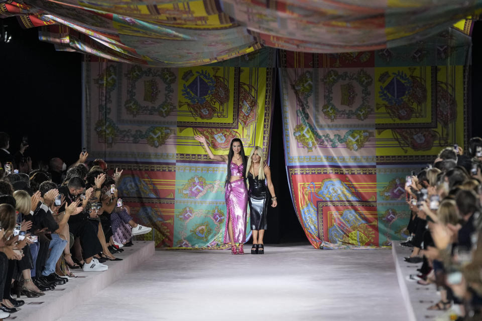 Dua Lipa, left, and Donatella Versace acknowledge applause at the conclusion of the Versace Spring Summer 2022 collection during Milan Fashion Week, in Milan, Italy, Friday, Sept. 24, 2021. (AP Photo/Luca Bruno)