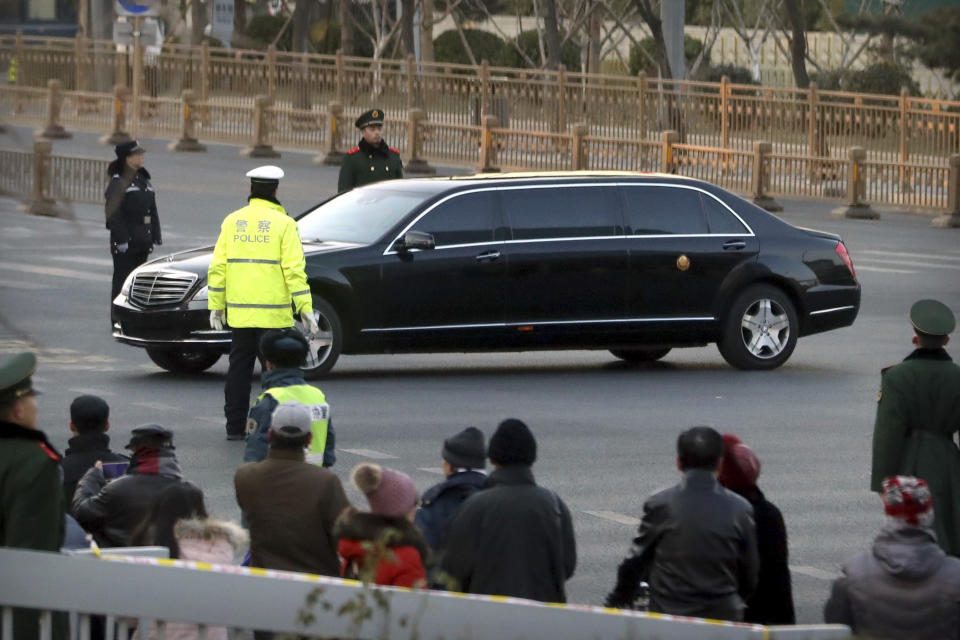 Spectators watch as security officials stand guard while a Mercedes limousine in a motorcade believed to be carrying North Korean leader Kim Jong Un passes along a street in Beijing, Wednesday, Jan. 9, 2019. North Korean state media reported Tuesday that Kim is making a four-day trip to China in what's likely an effort by him to coordinate with his only major ally ahead of a summit with U.S. President Donald Trump that could happen early this year. (AP Photo/Mark Schiefelbein)