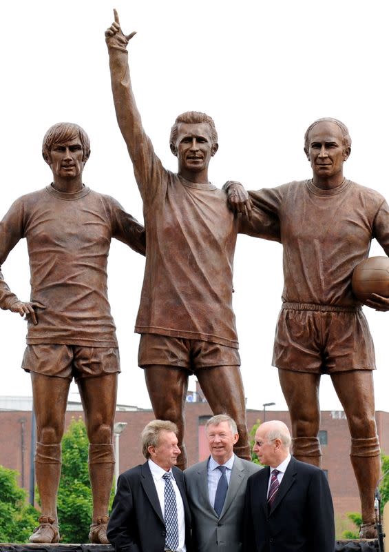 FILE PHOTO: Manchester United's coach Ferguson poses with Law and Charlton at the unveiling of a statue of former Manchester United players George Best, Denis Law and Bobby Charlton outside Old Trafford football ground in Manchester, northern England,