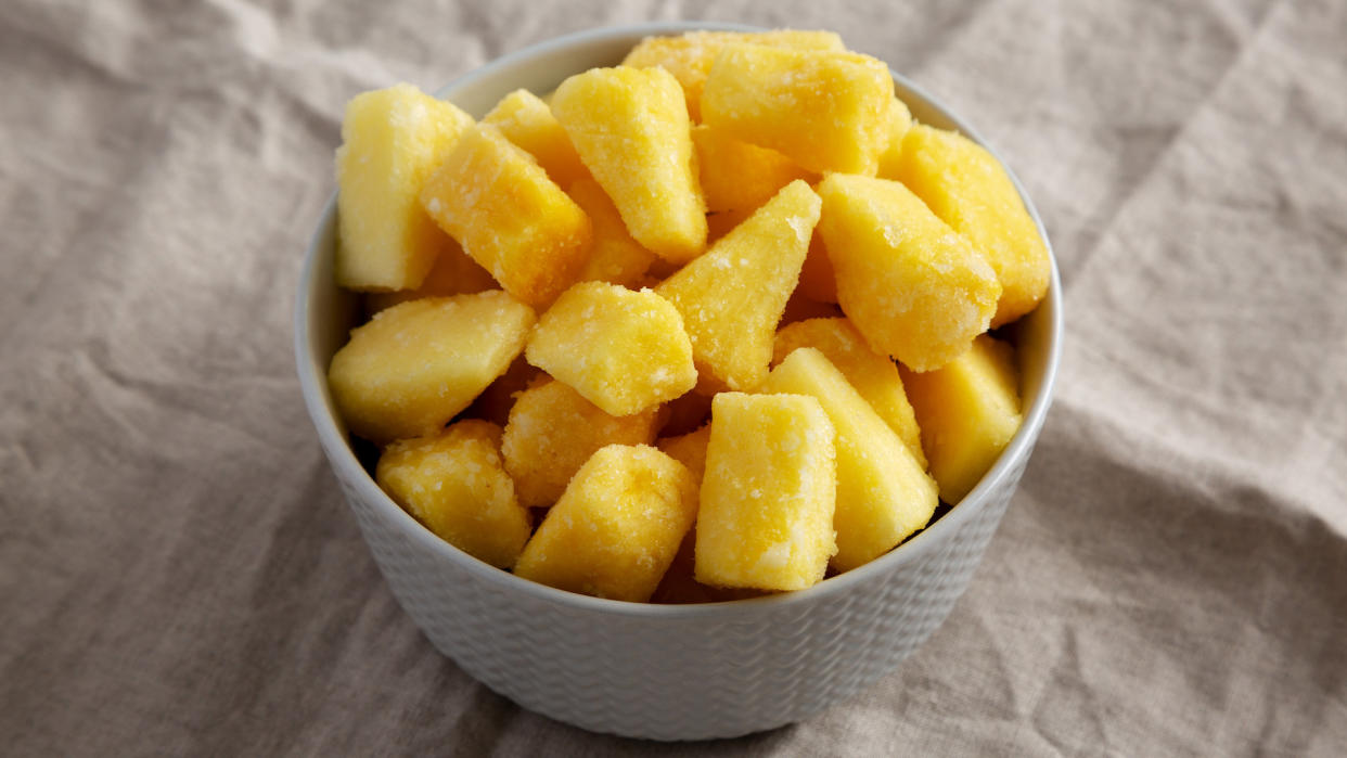  frozen pineapple in grey bowl on grey sheet 