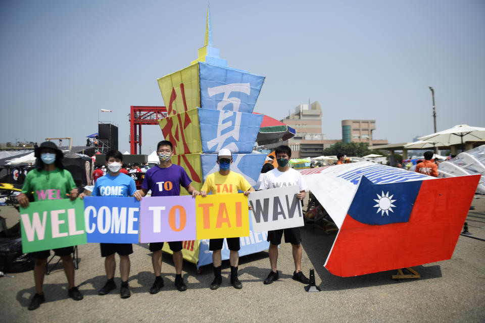 Participants hold up a welcome sign near a Taiwanese flag in Taichung, a port city in central Taiwan on Sunday, Sept. 18, 2022. Pilots with homemade gliders launched themselves into a harbor from a 20-foot-high ramp to see who could go the farthest before falling into the waters. It was mostly if not all for fun as thousands of spectators laughed and cheered on 45 teams competing in the Red Bull “Flugtag” event held for the first time. (AP Photo/Szuying Lin)