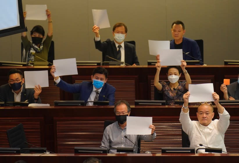Pro-democracy lawmakers raise white papers to protest during a meeting to discuss the new national security law at the Legislative Council in Hong Kong, Tuesday, July 7, 2020. (AP Photo/Vincent Yu)