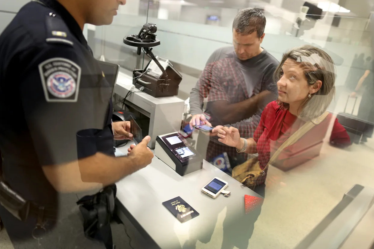 Dos viajeros hablan con un oficial de la Oficina de Aduanas y Protección Fronteriza (CBP) de EE. UU en el aeropuerto de Miami.  (Foto de Joe Raedle/Getty Images)