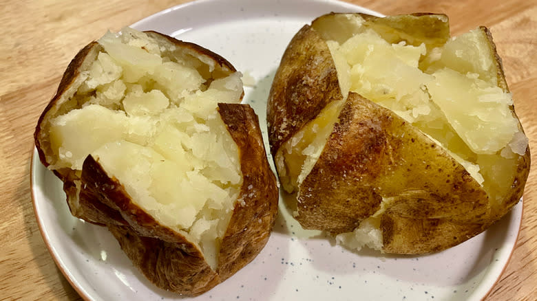 Two baked potatoes popped open to show interior