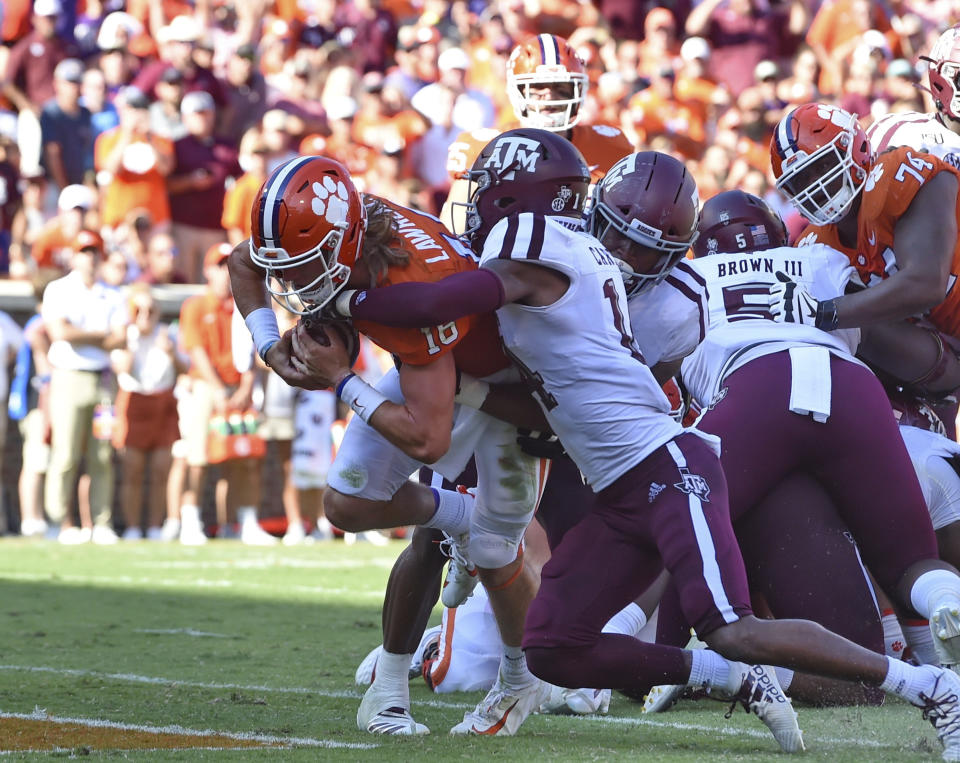 Clemson's Trevor Lawrence, left, scores a touchdown while being defended by Texas A&M's Keldrick Carper during the first half of an NCAA college football game Saturday, Sept. 7, 2019, in Clemson, S.C. (AP Photo/Richard Shiro)