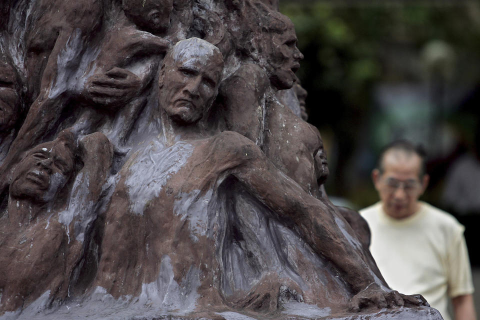 FILE - In this May 4, 2005, file photo, veteran pro-democracy activist Szeto Wah stands behind the "Pillar of Shame," during a ceremony to mark the May 4 movement in China at the Hong Kong University. Danish artist Jens Galschioet is seeking to get back his sculpture in Hong Kong memorializing the victims of China's 1989 Tiananmen Square crackdown as a deadline loomed for its removal Wednesday, Oct. 13, 2021. (AP Photo/Vincent Yu, File)