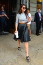 <p>In a cropped grey top and pleated leather skirt</p>