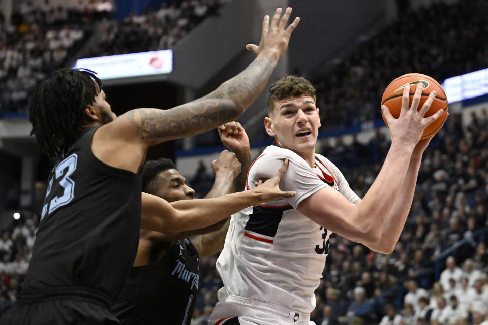 UConn center Donovan Clingan, right, is guarded by Marquette forward David Joplin, left, and Marquette guard Kam Jones, center, in the first half of an NCAA college basketball game, Saturday, Feb. 17, 2024, in Hartford, Conn. (AP Photo/Jessica Hill)