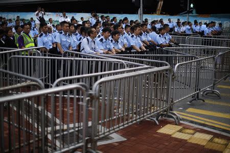 Policemen stand next to metal fences as protesters gather around the Golden Baihinia Square during an official flag raising ceremony to commemorate the Chinese National Day in Hong Kong, October 1, 2014. REUTERS/Carlos Barria