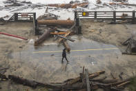 A California State Parks employee walks through a damaged road at Seacliff State Beach in Aptos, Calif., Thursday, Jan. 5, 2023. (AP Photo/Nic Coury)