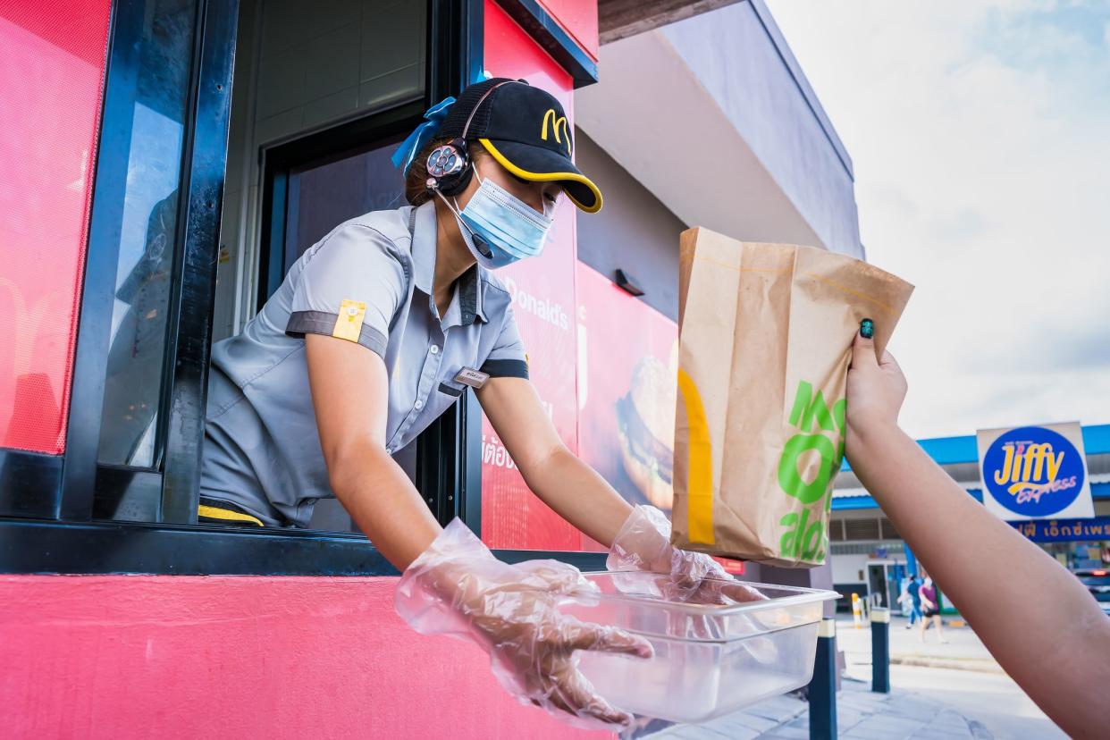 Bangkok, Thailand- April, 03, 2021 : Female staff at McDonald's deliver food to customers through the door of the car at the pick up point in Bangkok, Thailand