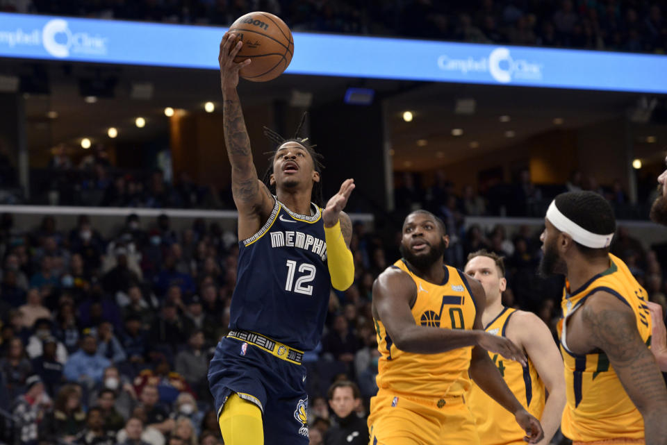 Memphis Grizzlies guard Ja Morant (12) looks to shoot ahead of Utah Jazz forward Eric Paschall (0) in the first half of an NBA basketball game Friday, Jan. 28, 2022, in Memphis, Tenn. (AP Photo/Brandon Dill)