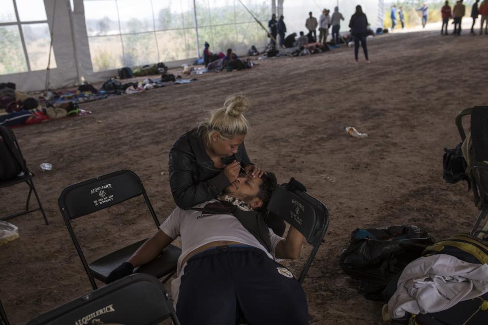 Central American migrant Jenifer Argueta plucks the eyebrows of Honduran Kevin Banegas, while waiting to receive donated food in Palmillas, Mexico, Saturday, Nov. 10, 2018. Thousands of Central American migrants were back on the move toward the U.S. border Saturday, after dedicated Mexico City metro trains whisked them to the outskirts of the capital and drivers began offering rides north. (AP Photo/Rodrigo Abd)