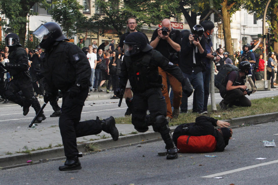 An anti-G-20 Summit protester lies on the ground as riot policemen charge during the clashes.