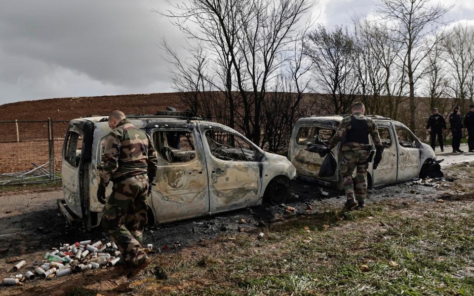 Soldiers walk around burned-out police vehicles after clashes with protesters in Sainte-Soline, western France - AP Photo/Jeremias Gonzalez