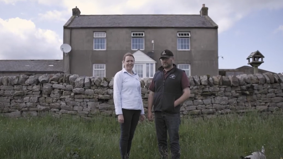Neil and Sarah Robson standing in front of their remote farmhouse