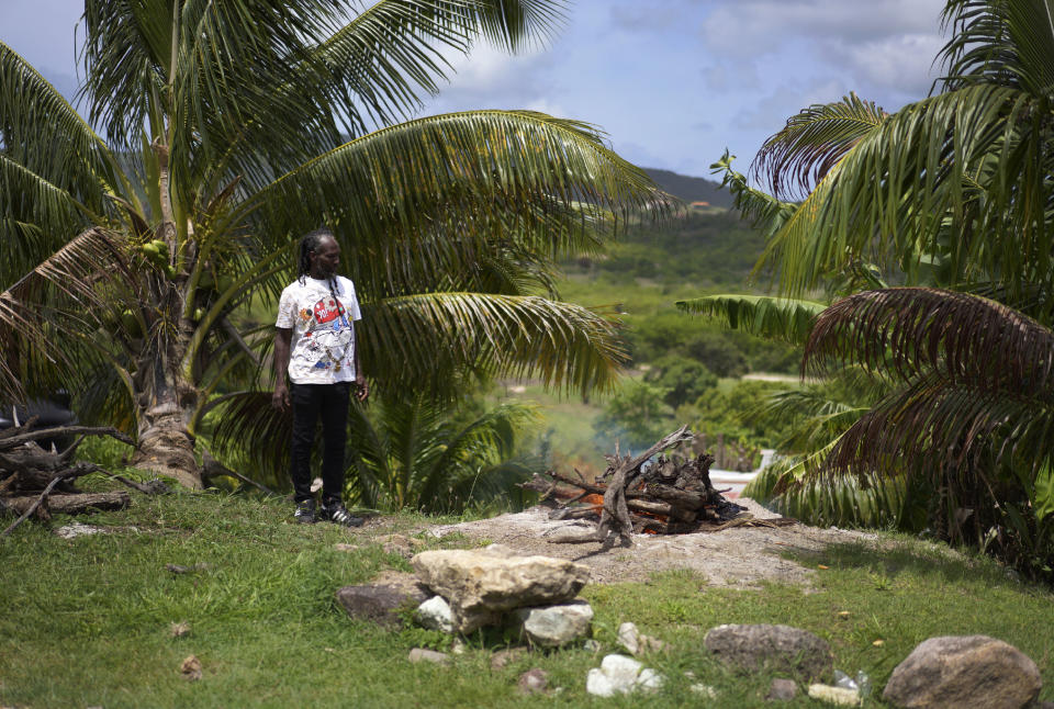 Ras Iko Francis builds a sacred Nyabinghi fire outside of the tabernacle where services are held at the Ras Freeman Foundation for the Unification of Rastafari, Sunday, May 14, 2023, in Liberta, Antigua. (AP Photo/Jessie Wardarski)