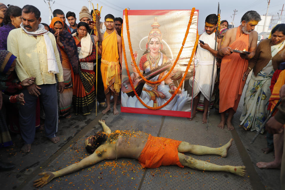 A Hindu Holy man lies in front of an image of Hindu Goddess of learning Saraswati, at Sangam, the sacred confluence of the rivers Ganga, Yamuna and the mythical Saraswati, during Magh Mela festival, in Prayagraj, India. Tuesday, Feb. 16, 2021. Hindus believe that ritual bathing on auspicious days can cleanse them of all sins. A tented city for the religious leaders and the believers has come up at the sprawling festival site with mounted police personnel keeping a close watch on the activities. The festival is being held amid rising COVID-19 cases in some parts of India after months of a steady nationwide decline. (AP Photo/Rajesh Kumar Singh)