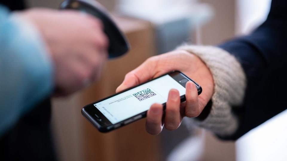 Eine Frau lässt am Eingang eines Corona-Schnelltest-Zentrums einen QR-Code auf ihrem Smartphone abscannen.