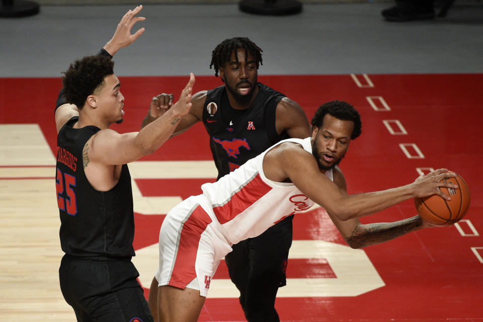 Houston forward Justin Gorham, right, looks to pass as SMU forward Ethan Chargois, left, and Emmanuel Bandoumel, back, defends during the first half of an NCAA college basketball game, Sunday, Jan. 31, 2021, in Houston. (AP Photo/Eric Christian Smith)