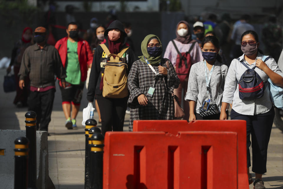 People wear face masks as a precaution against the new coronavirus as they walk on a street in Jakarta, Indonesia Monday, June 8, 2020. Indonesia’s capital of Jakarta, the city hardest hit by the new coronavirus, has partly reopened after two months of partial lockdown as the world’s fourth most populous nation braces to gradually reopen its economy. (AP Photo/Achmad Ibrahim)