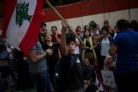 A boy waves a Lebanese national flag as demonstrators take part in an anti-government protest outside the Central Bank of Lebanon in Beirut