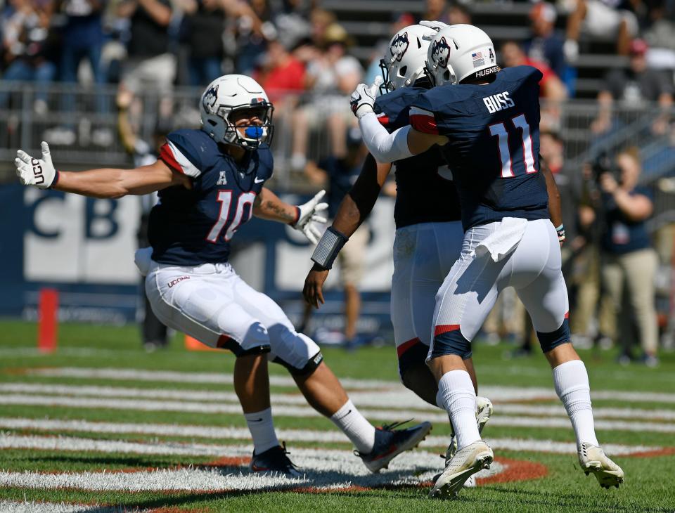 Connecticut quarterback David Pindell, center, celebrates a touchdown with teammates Zavier Scott, 10, and Kyle Buss, 11, during an NCAA college football game last September against Rhode Island.