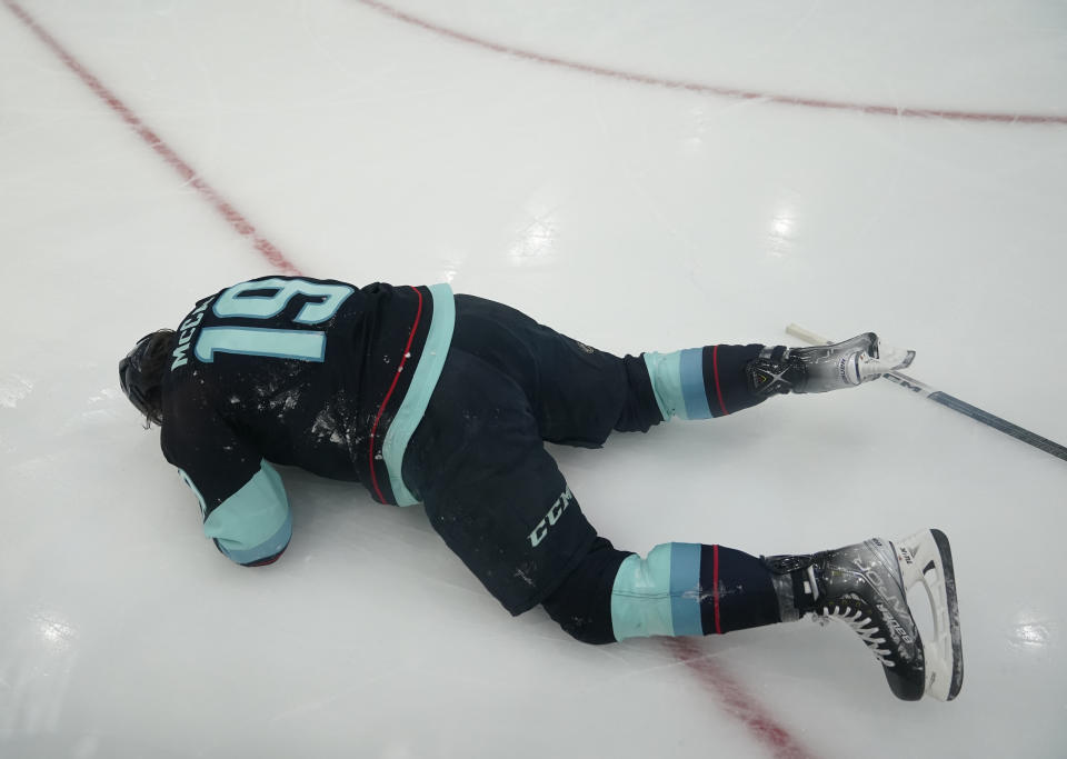 Seattle Kraken left wing Jared McCann (19) lies on ice after being hit by Colorado Avalanche defenseman Cale Makar during the first period of Game 4 of an NHL hockey Stanley Cup first-round playoff series Monday, April 24, 2023, in Seattle. McCann left the game. (AP Photo/Lindsey Wasson)