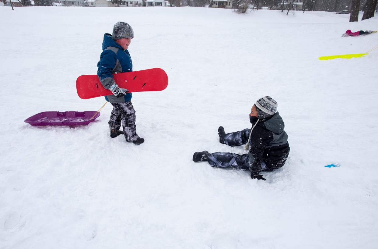 bram Barrons, then-age 8, left, carries a snowboard and pulls a sled for his friend Cameron Johnson, then-7, while he sits n the snow Tuesday, Jan. 29, 2019 on the sledding hill outside Palmer Park Recreation Center.
