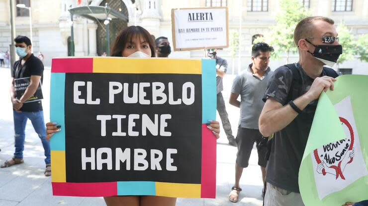 Eine junge Frau hält vor dem Sitz der Stadtverwaltung von Madrid ein Schild mit der Aufschrift „Die Menschen haben Hunger