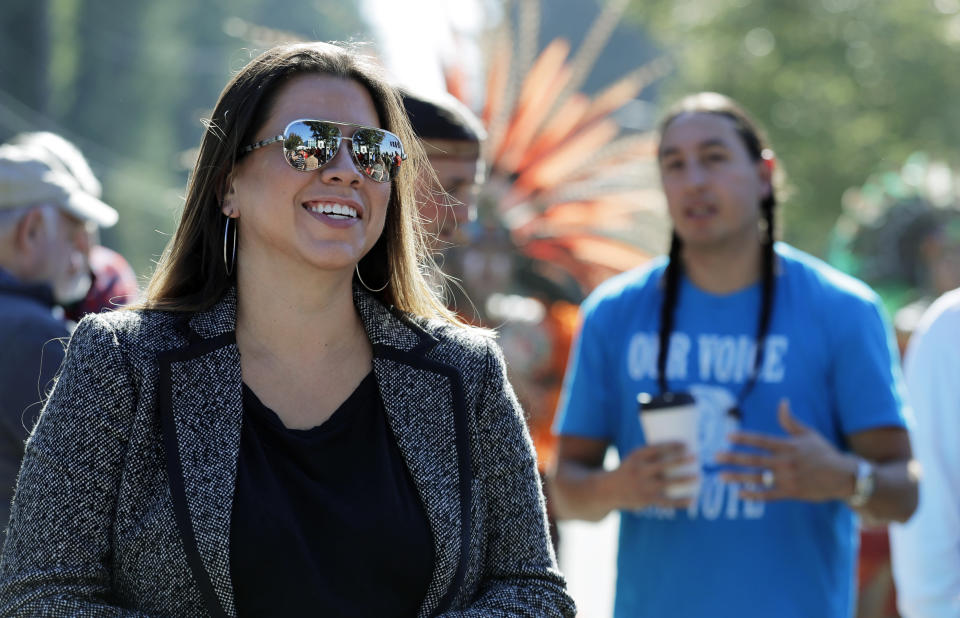 CORRECTS TO WILLIS’ TRIBE REQUIRES 1/4 NATIVE AMERICAN BLOOD, AND A GRANDPARENT OR PARENT TO BE ENROLLED IN THE TRIBE - In this Oct. 17, 2018 photo, Nicole Willis, left, a member of the Confederated Tribes of the Umatilla Reservation who lives in Seattle, listens to speakers at a rally in Lacey, Wash. Elizabeth Warren's spat with Donald Trump over Warren's Native American heritage has brought global attention to what it means to be Native American. Willis believes being Native American means her family is part of a distinct, interconnected community that has existed since ancient times. Willis’ tribe requires 1/4 Native American blood, and a grandparent or parent to be enrolled in the tribe but she said “theoretically, it shouldn’t matter.”(AP Photo/Ted S. Warren)