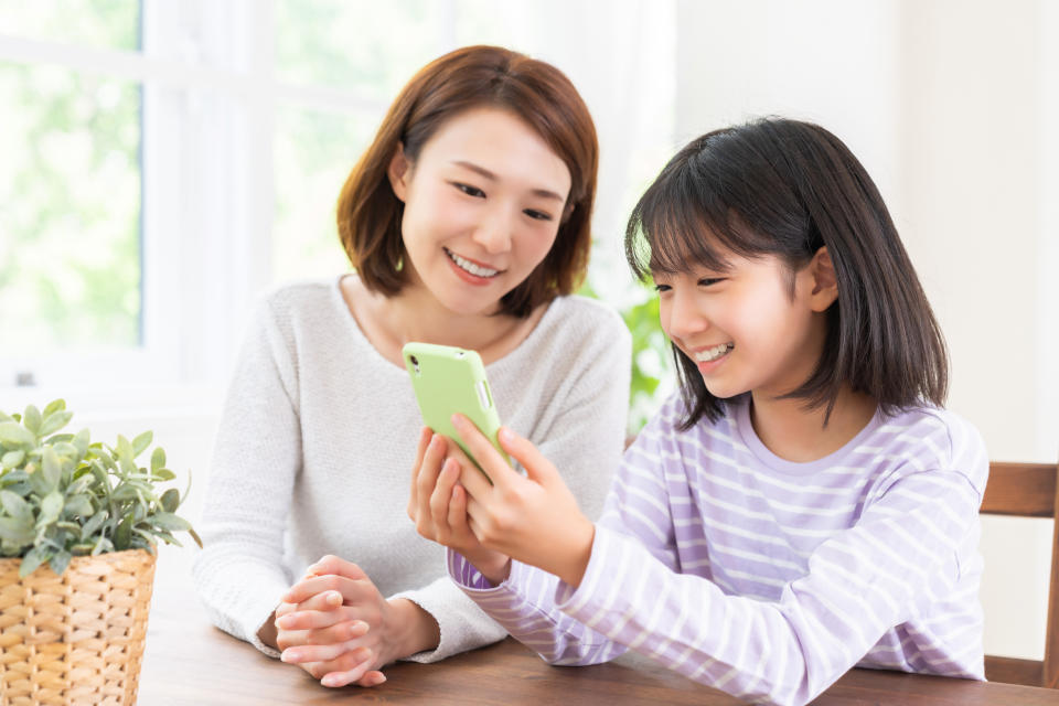 Young asian mother and daughter using a smart phone