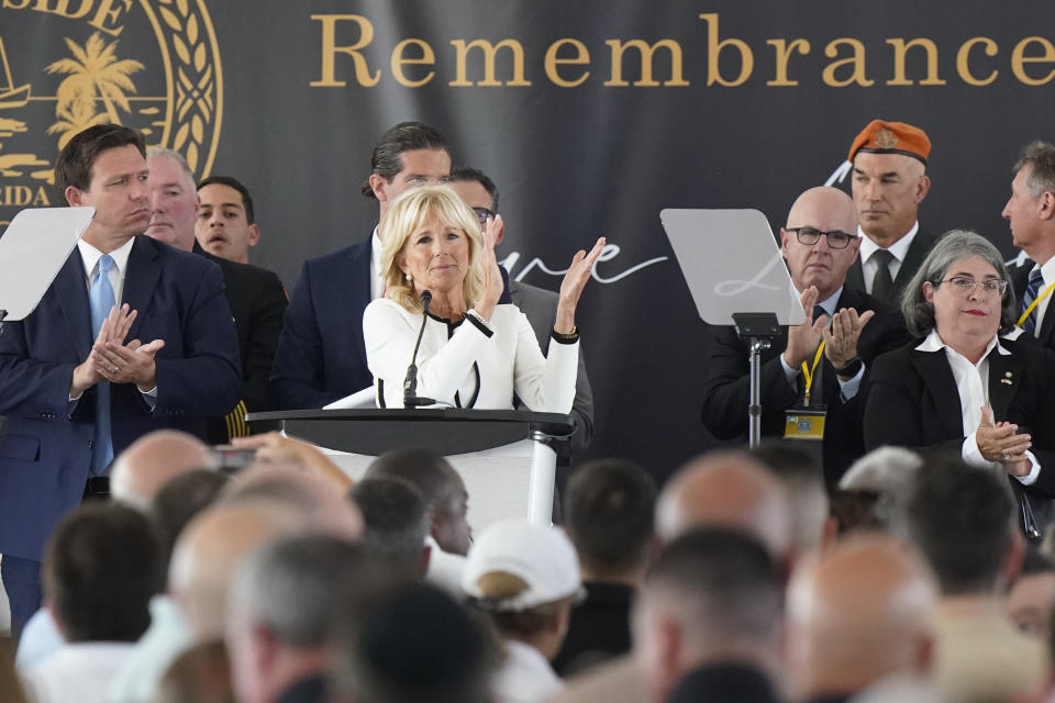 First lady Jill Biden, center, leads a round of applause for first responders during a remembrance event at the site of the Champlain Towers South building collapse, Friday, June 24, 2022, in Surfside, Fla. Friday marks the anniversary of the oceanfront condo building collapse that killed 98 people in Surfside. The 12-story tower came down with a thunderous roar and left a giant pile of rubble in one of the deadliest collapses in U.S. history. (AP Photo/Wilfredo Lee)