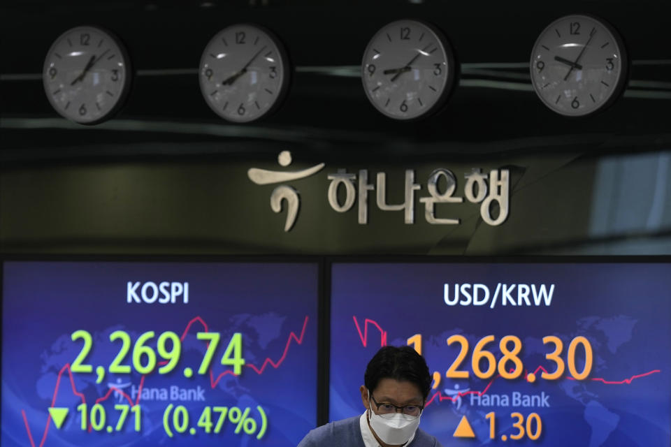 A currency trader walks by the screens showing the Korea Composite Stock Price Index (KOSPI), left, and the foreign exchange rate between U.S. dollar and South Korean won at a foreign exchange dealing room in Seoul, South Korea, Thursday, Dec. 29, 2022. Shares slipped in Asia on Thursday after benchmarks fell more than 1% on Wall Street in the middle of a mostly quiet and holiday-shortened week. (AP Photo/Lee Jin-man)