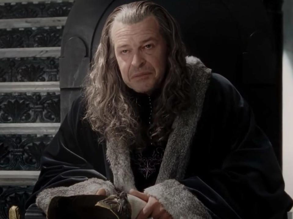Denethor sitting on a throne wearing a black coat in lord of the rings