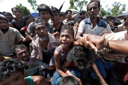 A boy is pulled to safety as Rohingya refugees scuffle while queueing for aid at Cox's Bazar, Bangladesh, September 26, 2017. REUTERS/Cathal McNaughton