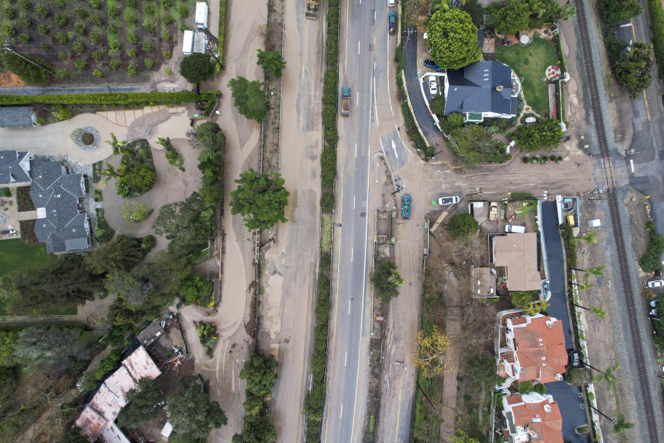 In an aerial view, a flooded area by the overflowing San Ysidro creek on Jameson Lane is seen near the closed Highway 101 in Montecito, Calif., Tuesday, Jan. 10, 2023. California saw little relief from drenching rains Tuesday as the latest in a relentless string of storms swamped roads, turned rivers into gushing flood zones and forced thousands of people to flee from towns with histories of deadly mudslides. (AP Photo/Ringo H.W. Chiu)