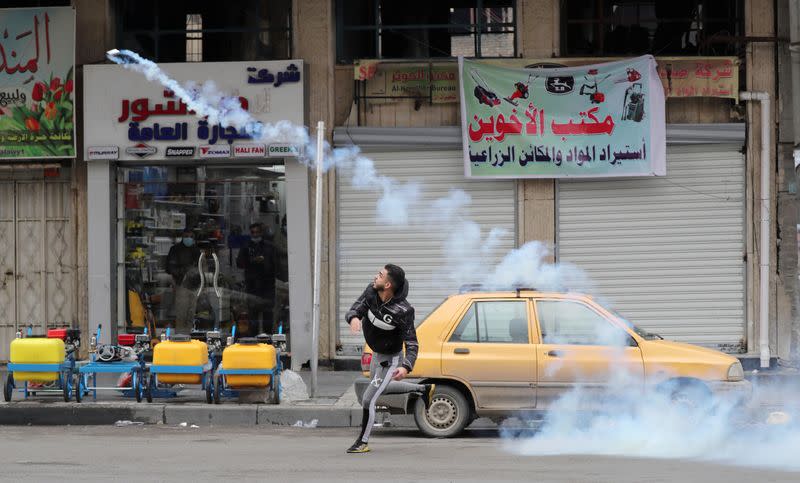 A demonstrator throws a tear gas canister back at the Iraqi security forces during ongoing anti-government protests in Baghdad