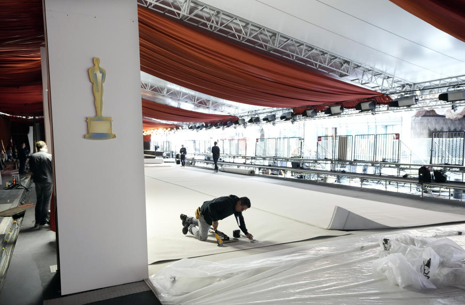 Un trabajador engrapa una alfombra blanca durante los preparativos para la 95a edición de los Premios de la Academia, el 8 de marzo de 2023, fuera del Teatro Dolby en Los Angeles. (Foto AP/Chris Pizzello)