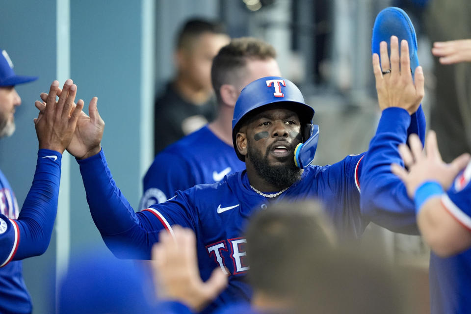 Texas Rangers' Adolis Garcia celebrates in the dugout after scoring against the Los Angeles Dodgers during the third inning of a baseball game Thursday, June 13, 2024, in Los Angeles. (AP Photo/Ryan Sun)